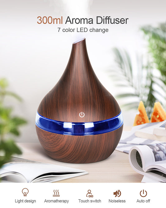 Wooden aroma diffuser with LED lights on a table with books and plants