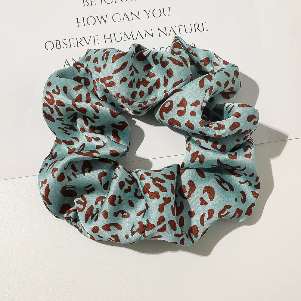 Blue scrunchie with brown leopard print pattern on a light background