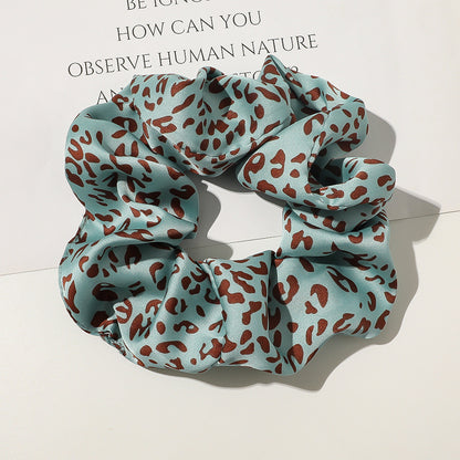 Blue scrunchie with brown leopard print pattern on a light background