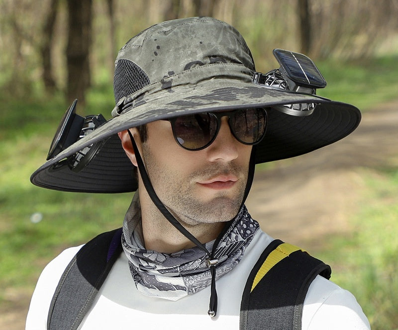 Person wearing a large sun hat with solar battery and fans, outdoors.