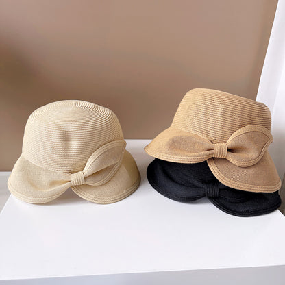 Two straw hats with bow details on a white surface against a beige background