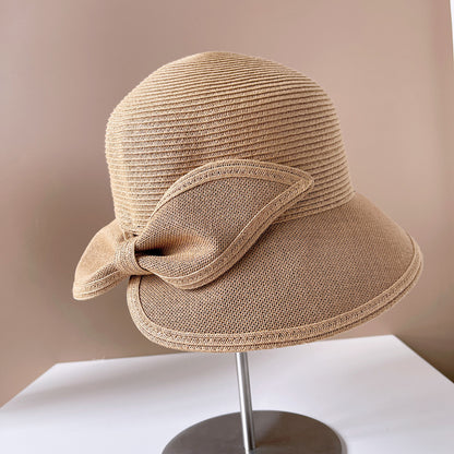 Beige straw hat with a bow on a mannequin head against a beige background